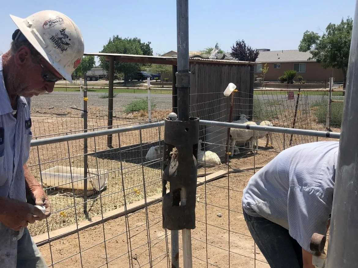 Crew member in a hard hat and a coworker working at a well head