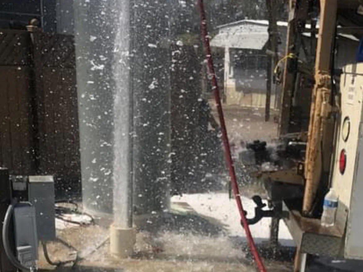 Drill rig at work with water spraying up from the new well bore