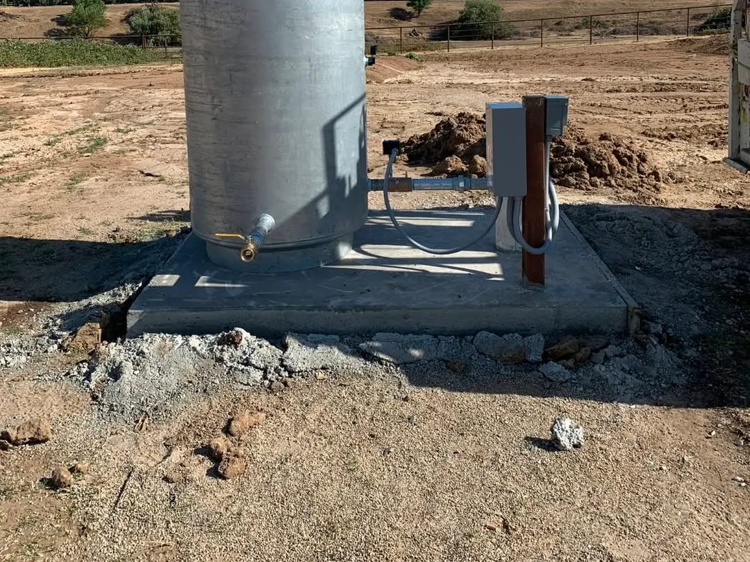 Galvanized pressure tank on a concrete pad beside a well head