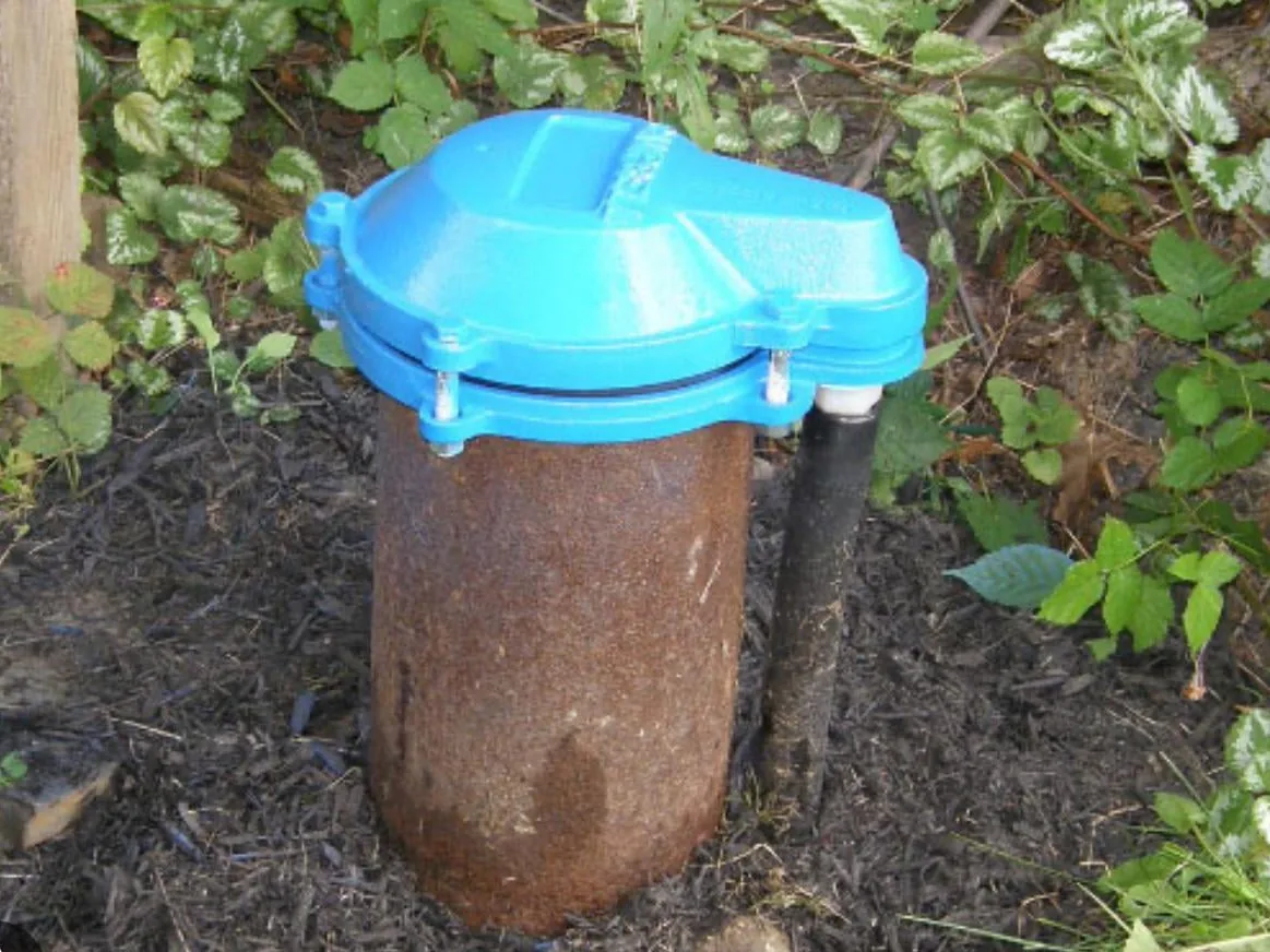 Well cap bolted onto a steel well casing with an electrical conduit alongside
