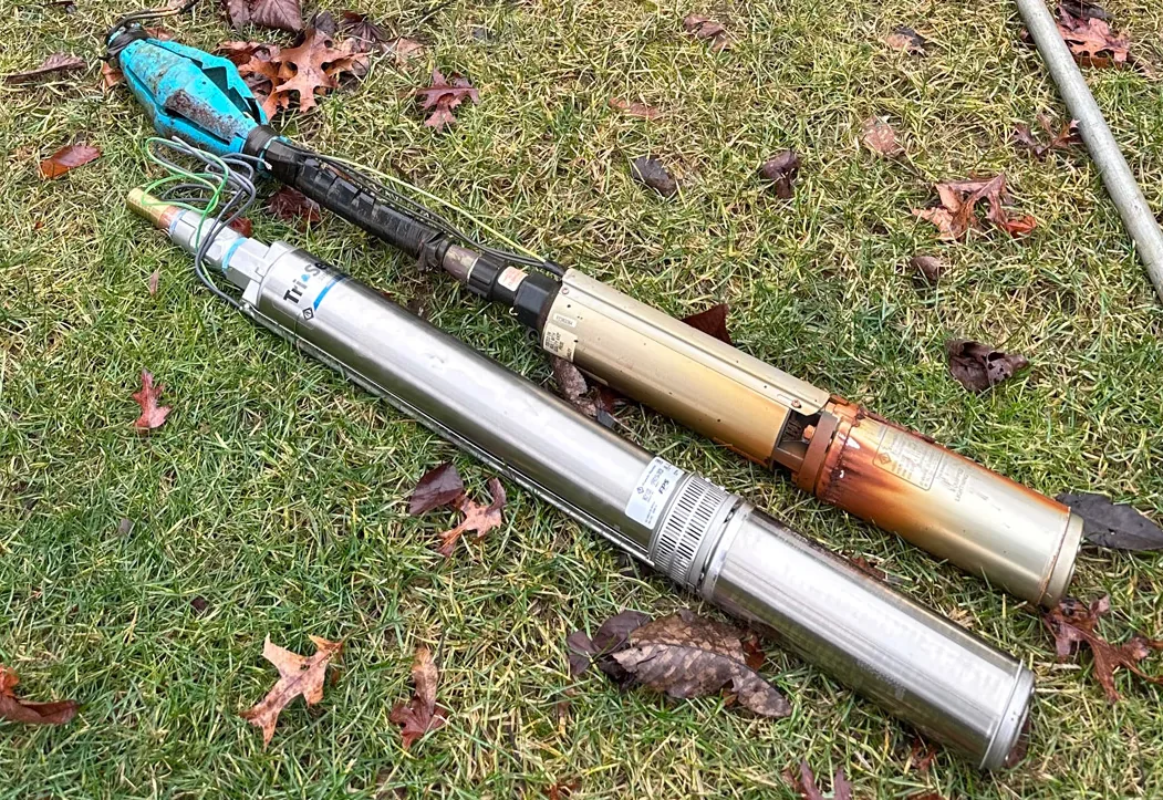 Worn submersible well pump pulled from a well lying beside its new stainless replacement